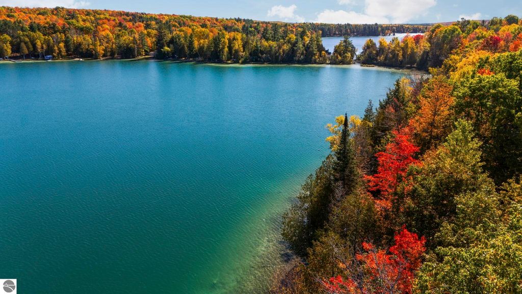 Scenic view of North Blue Lake with vibrant fall foliage, showcasing the natural beauty and tranquility of the Blue Lake Heights community in Kalkaska, MI.