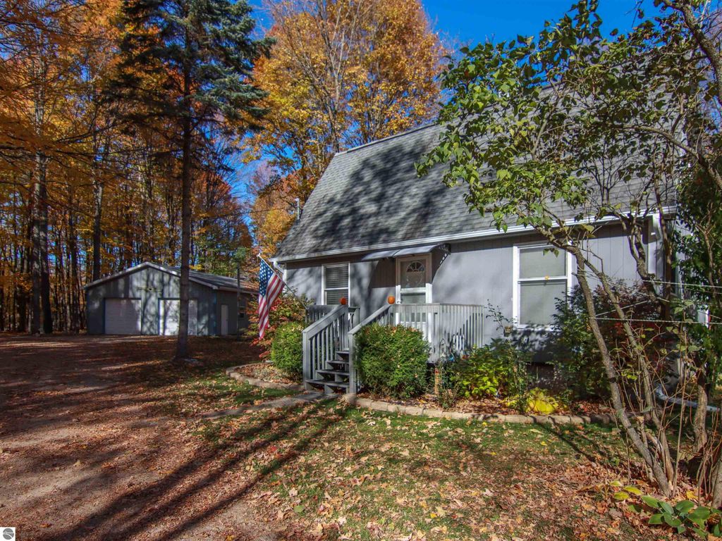 3-bedroom, 2-bath saltbox style home on 8.75 acres with detached pole barn, surrounded by autumn foliage and featuring a welcoming front porch.