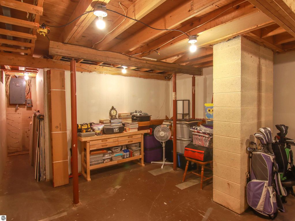Basement storage area featuring organized shelving, golf clubs, and a fan, highlighting additional space in the 3-bed, 2-bath home for sale at 20280 Cadillac Highway, Copemish, MI.