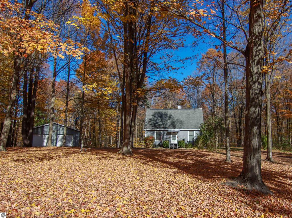 3-bedroom, 2-bathroom saltbox home on 8.75 acres surrounded by autumn foliage, featuring a detached pole barn, located at 20280 Cadillac Highway, Copemish, MI.