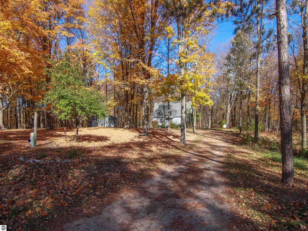 Residential home at 20280 Cadillac Highway, surrounded by autumn foliage and trees, showcasing the driveway leading to the house on 8.75 acres in Copemish, MI.