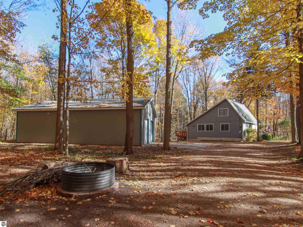 Saltbox style home with detached pole barn on wooded property, surrounded by autumn foliage, located at 20280 Cadillac Highway, Copemish, MI.