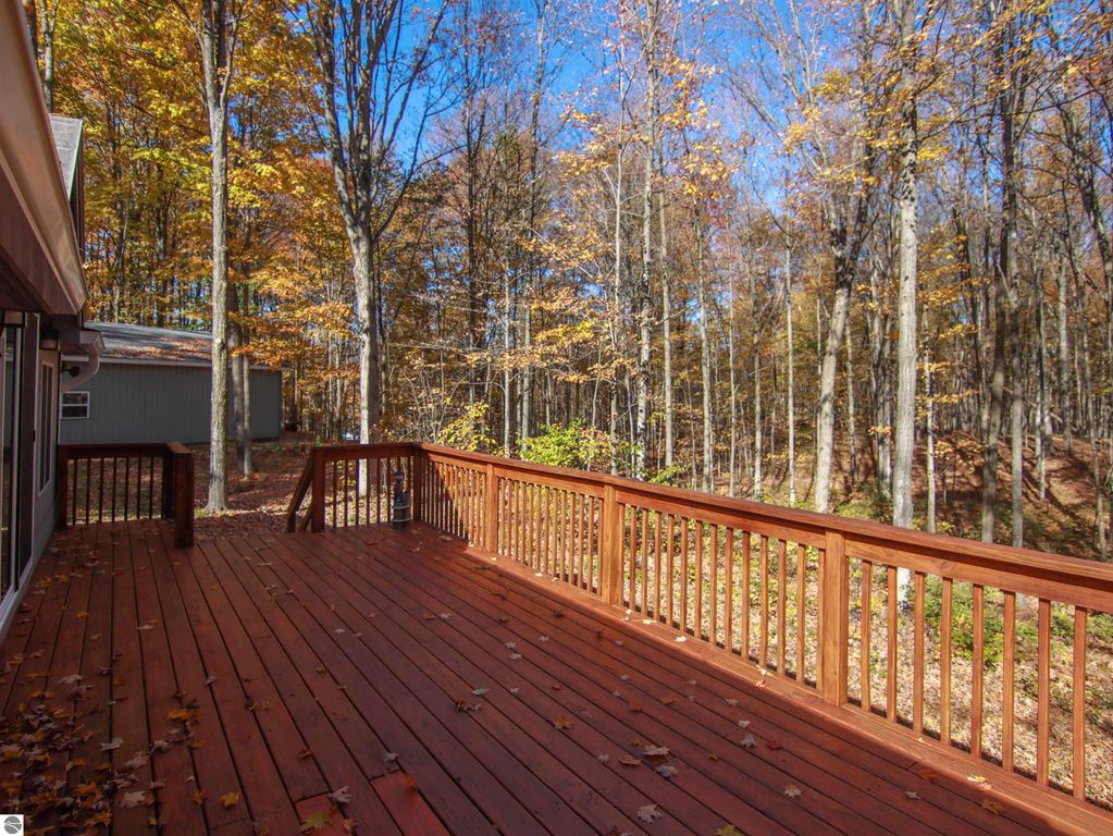 Deck overlooking wooded area with autumn foliage, showcasing the serene outdoor space of the 3-bedroom, 2-bathroom home at 20280 Cadillac Highway, Copemish, MI.
