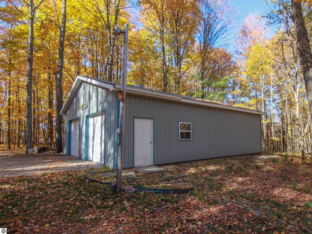 Detached 30x40 pole barn with two garage doors, surrounded by autumn foliage, near 20280 Cadillac Highway, Copemish, MI, highlighting property features for sale.