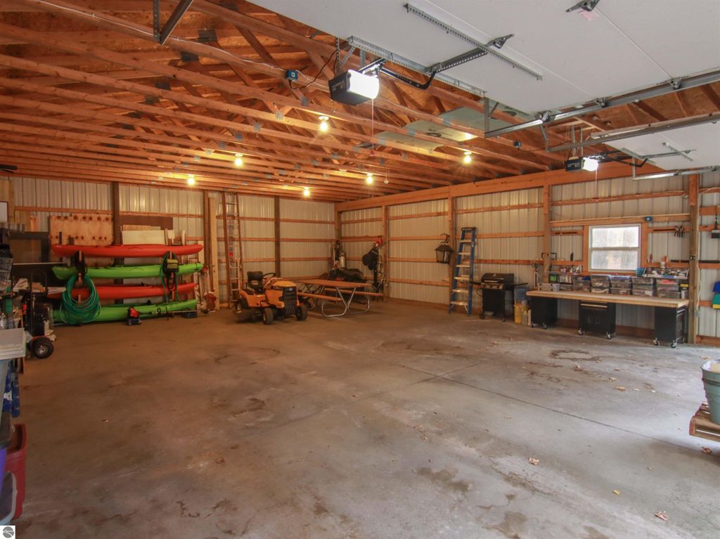 Spacious detached pole barn garage with storage for vehicles, kayaks, and tools, featuring ample lighting and organized workspace, located at 20280 Cadillac Highway, Copemish, MI.