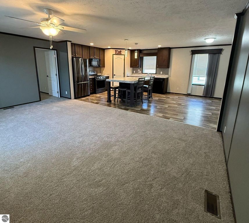 Spacious living area of 3 bedroom, 2 bathroom home for sale at 1032 Pebble Creek, featuring modern kitchen with island, dining space, and new carpet.