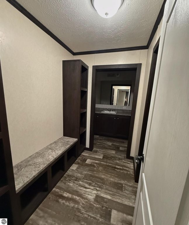 Interior view of a hallway with built-in shelving and a bench, leading to a bathroom area in a 3-bedroom home for sale at 1032 Pebble Creek, Mt Pleasant, MI, featuring modern finishes and a spacious layout.