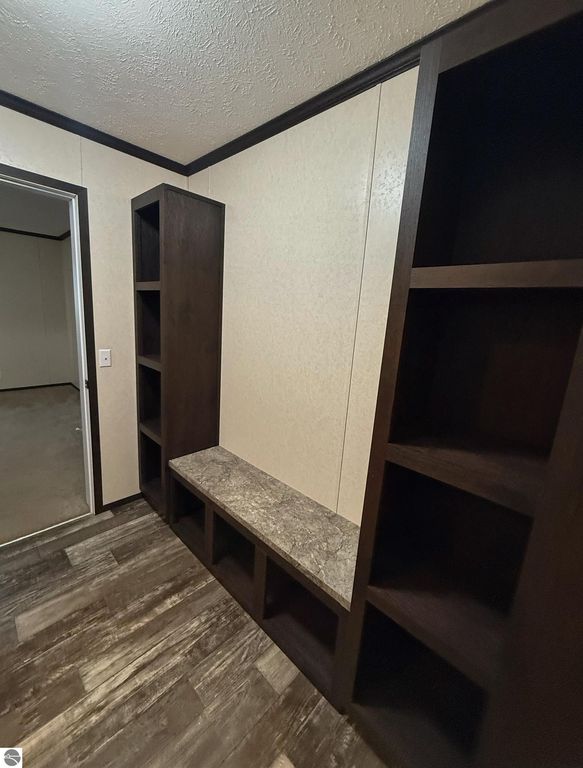 Interior view of a home entryway featuring built-in dark wood shelving and a stone bench, showcasing a modern design in a 3-bedroom, 2-bathroom home for sale in Mt Pleasant, MI.