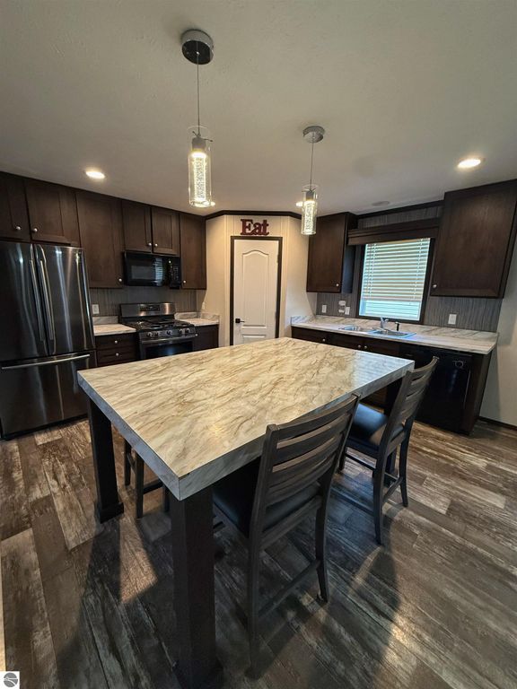 Modern kitchen with dark cabinetry, large island, and upgraded appliances, featuring an open layout and natural light.