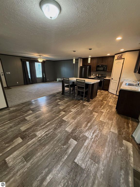 Open kitchen and dining area in a 3-bedroom home for sale at 1032 Pebble Creek, featuring modern cabinetry, large island, and new flooring, with a spacious living room visible in the background.