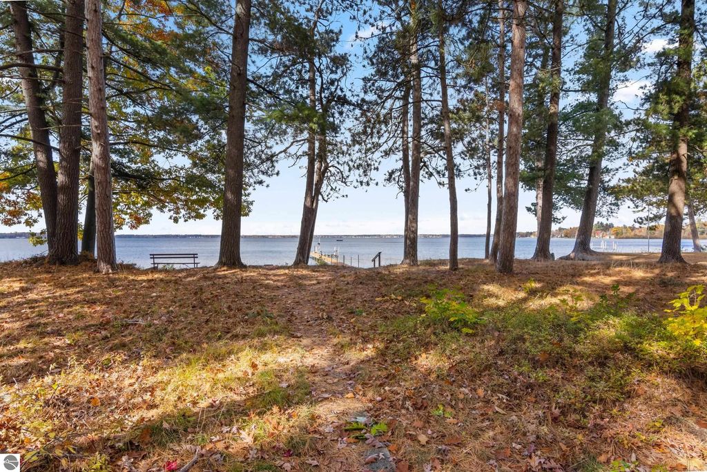 Wooded area with lake view at 396 Davenport Lane, Cadillac, MI, featuring a bench and pathway leading to Lake Mitchell, emphasizing serene outdoor setting and recreational opportunities.