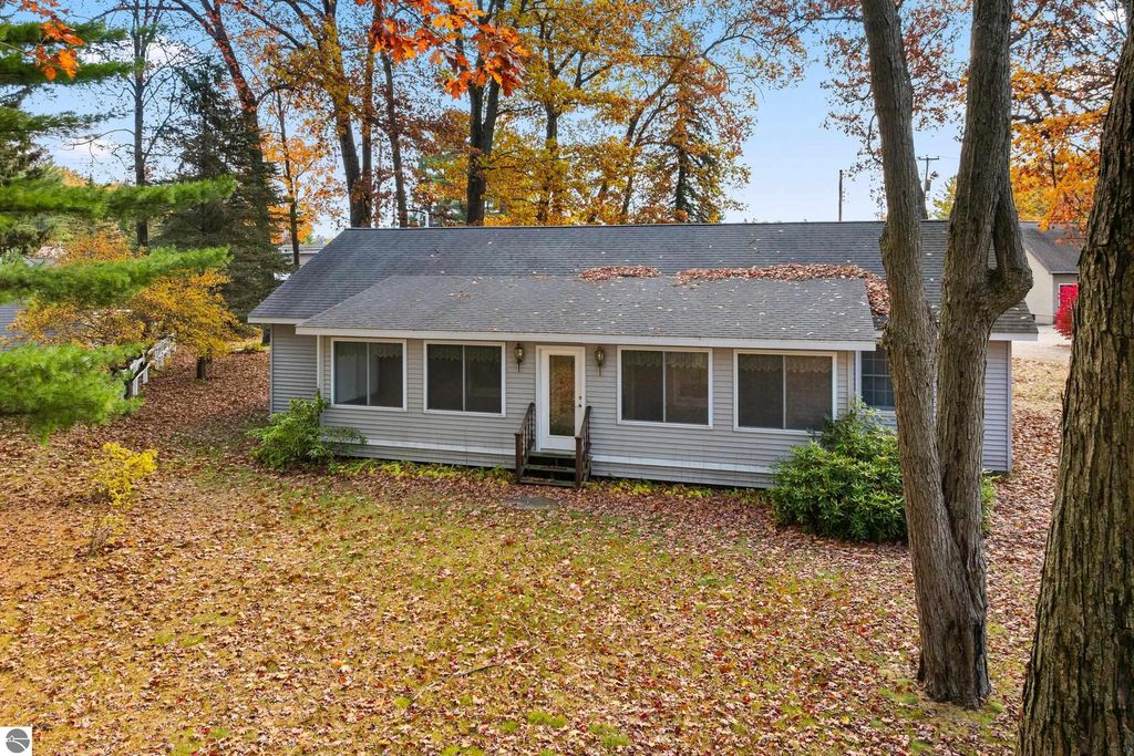 Charming single-story home at 396 Davenport Lane, surrounded by autumn foliage, featuring a welcoming front porch and large windows, set in a wooded area near Lake Mitchell.