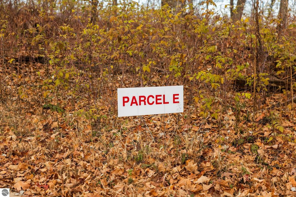 Sign marking "Parcel E" in a wooded area with autumn leaves, indicating a land parcel in a new development near Rapid City, MI.