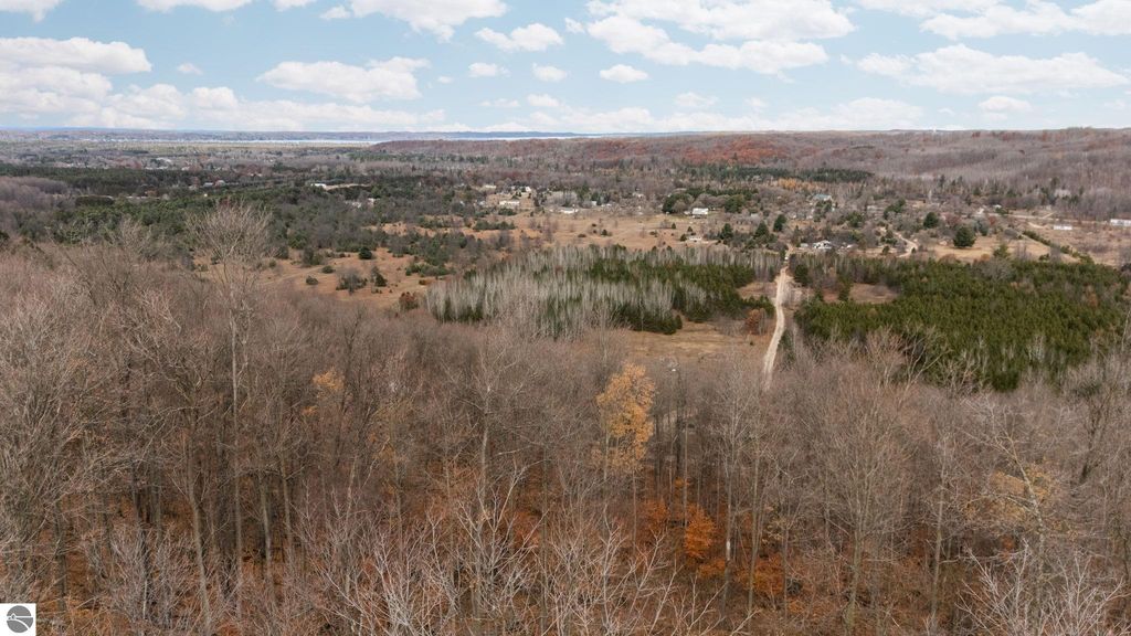 Aerial view of wooded land with rolling hills and private roads, showcasing 5.51 acres of property near Rapid City, MI, ideal for building a home or retreat.