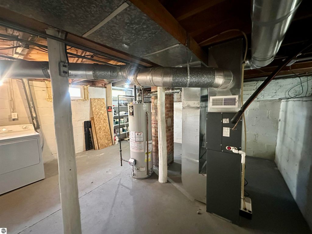 Basement interior with water heater and furnace, showcasing clean, dry space with new windows, relevant to Traverse City home listing at 209 W Fifteenth Street.