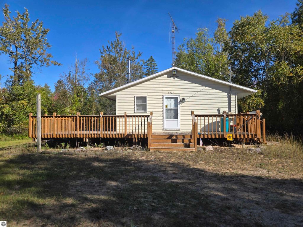 Cozy 2-bedroom, 1-bathroom home on a large wooded 25.21-acre lot in Harrisville, MI, featuring a spacious wrap-around deck and surrounded by nature.