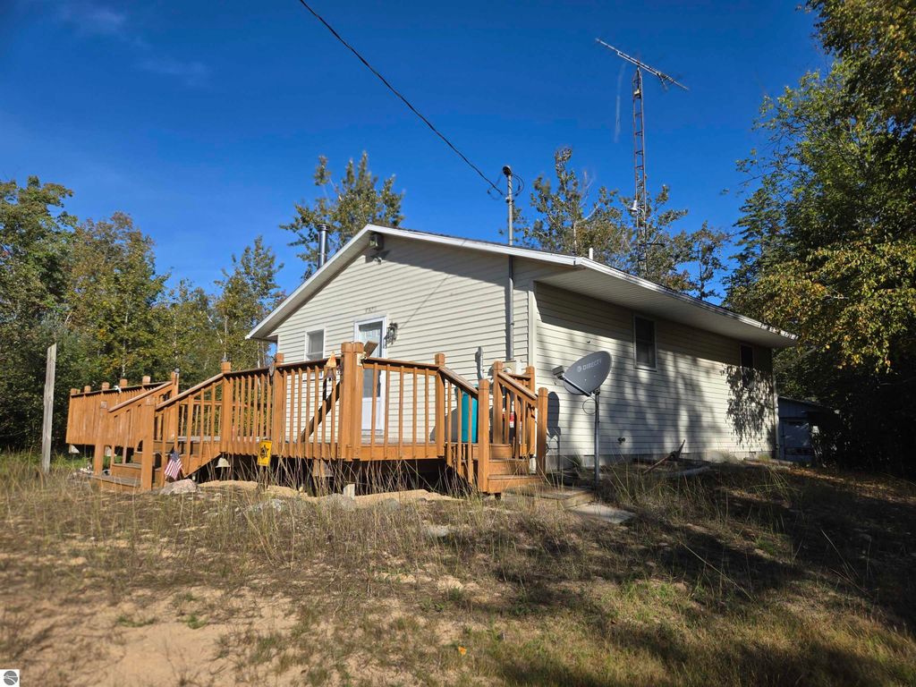 Cozy 2-bedroom, 1-bathroom home with large wrap-around deck on a wooded 25.21-acre lot in Harrisville, MI, adjacent to Sturgeon Point State Park.