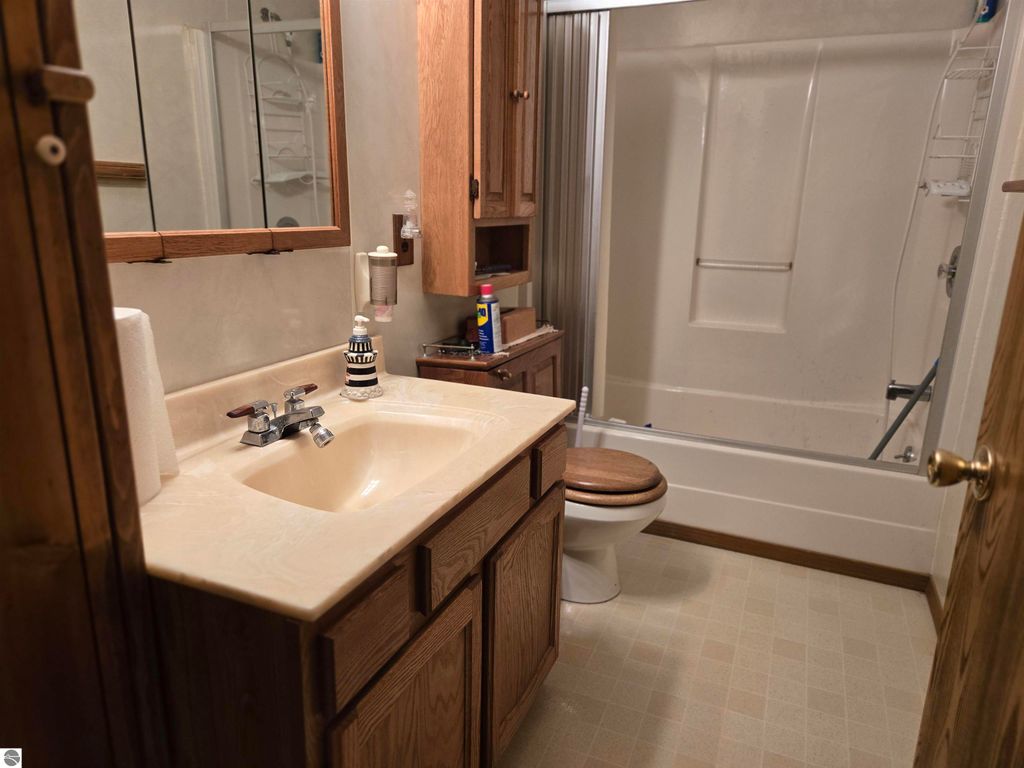 Bathroom with wooden cabinetry, sink, and shower/tub combination, featuring a cozy and functional design, suitable for a 2-bedroom home in Harrisville, MI.