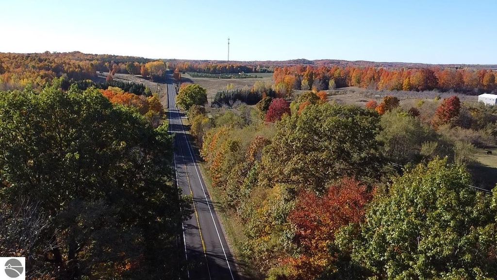 Aerial view of a scenic road surrounded by vibrant autumn foliage in Bear Lake, MI, showcasing the natural beauty and rural landscape near the property at 8721 Glover Lake Road.