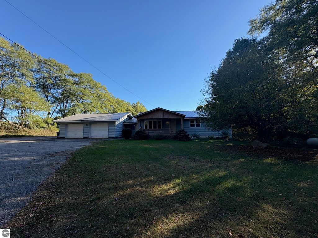 Ranch-style home at 8721 Glover Lake Road, Bear Lake, MI, featuring a large front yard, two-car garage, and surrounded by trees, showcasing a peaceful residential setting.