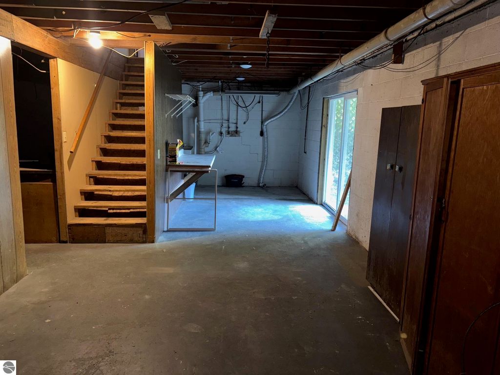 Basement interior of ranch-style home at 8721 Glover Lake Road, featuring stairs, utility area, and large windows for natural light.