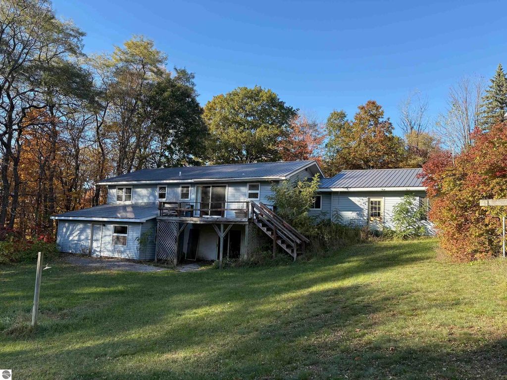 Ranch-style home at 8721 Glover Lake Road, Bear Lake, MI, featuring a large living room, walkout basement, and surrounded by trees on nearly 5 acres.