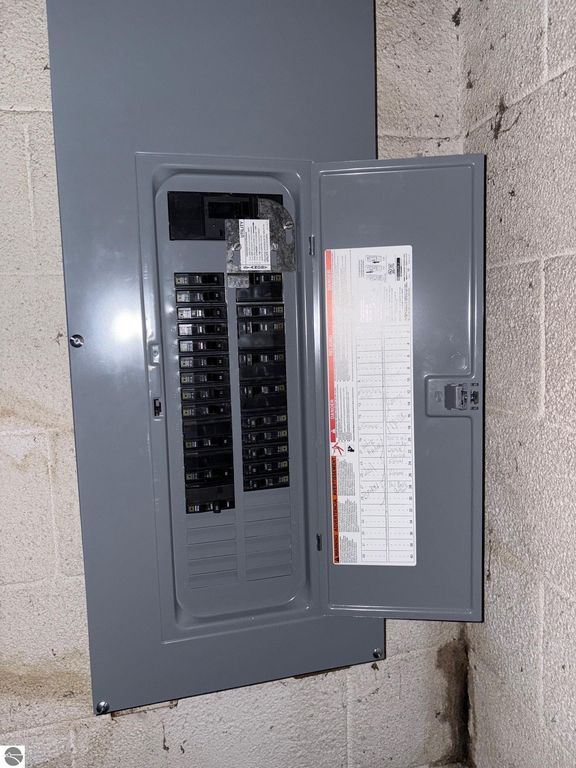 Electrical panel in the basement of a ranch-style home at 8721 Glover Lake Road, Bear Lake, MI, showcasing circuit breakers and safety information.