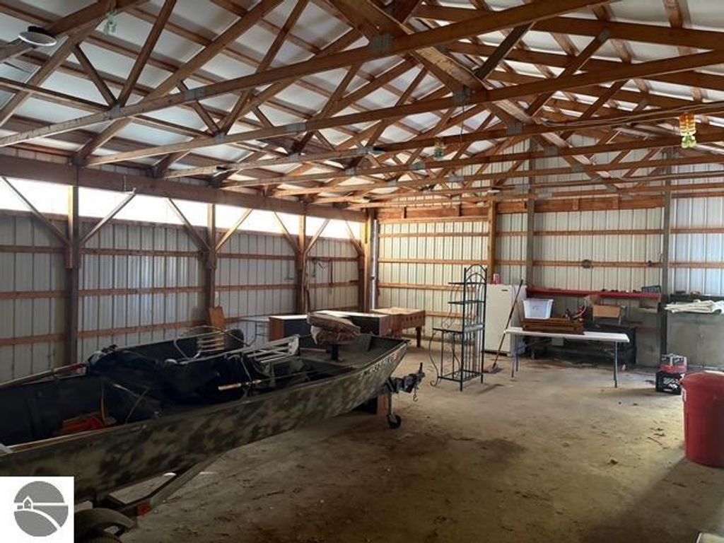 Interior of a 30 x 40 pole barn with wooden beams, concrete floor, and a boat, showcasing ample storage space for equipment and tools near Bear Lake, MI.