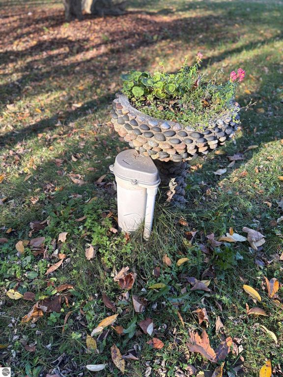 Flower planter made of stones atop a utility post, surrounded by autumn leaves and grass in a yard near 8721 Glover Lake Road, Bear Lake, MI.