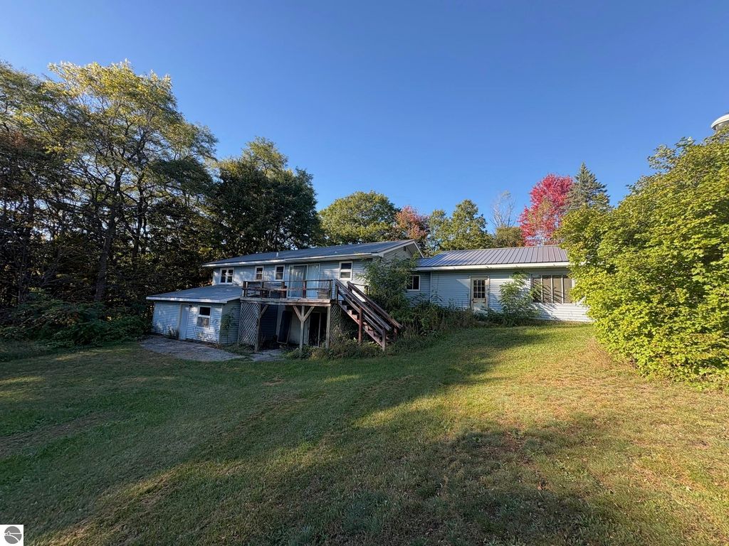 Ranch-style home at 8721 Glover Lake Road, Bear Lake, MI, featuring a large backyard, deck, and surrounding greenery, highlighting its 4.68 acres of land.