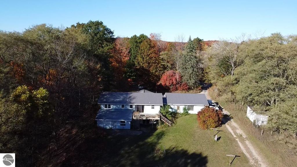 Aerial view of ranch-style home at 8721 Glover Lake Road, surrounded by autumn foliage, showcasing a large yard and nearby wooded area, highlighting the property's 4.68 acres.