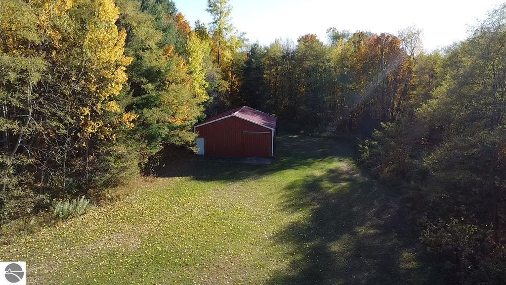Red barn structure surrounded by colorful autumn foliage and grassy area, located on 4.68 acres at 8721 Glover Lake Road, Bear Lake, MI, highlighting additional storage options for the property.