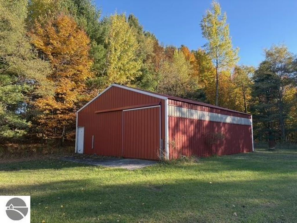 Red pole barn with 10' sidewalls and sliding doors, surrounded by colorful autumn trees on a property near Bear Lake, MI.