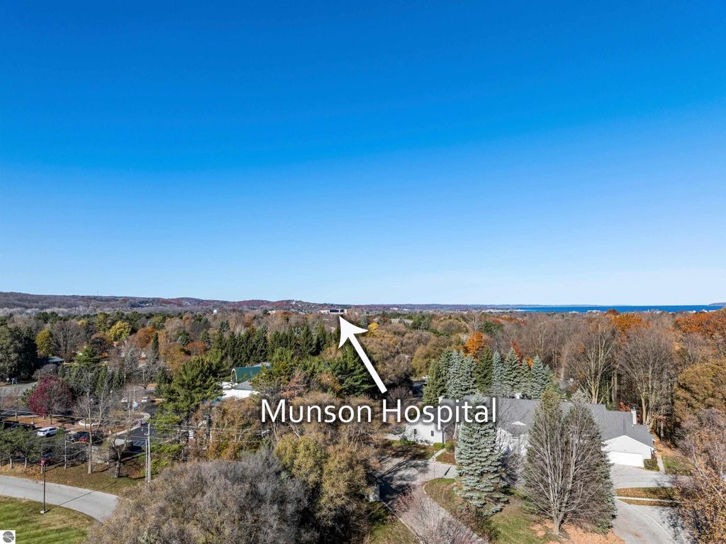 Aerial view of Traverse City, Michigan, highlighting Munson Hospital with directional arrow, showcasing the surrounding residential area and autumn foliage.