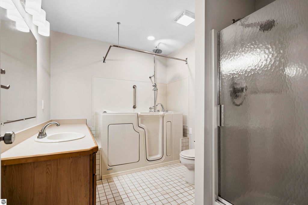Updated bathroom featuring a walk-in tub, separate shower, and modern fixtures, designed for comfort and accessibility in a Traverse City condo.