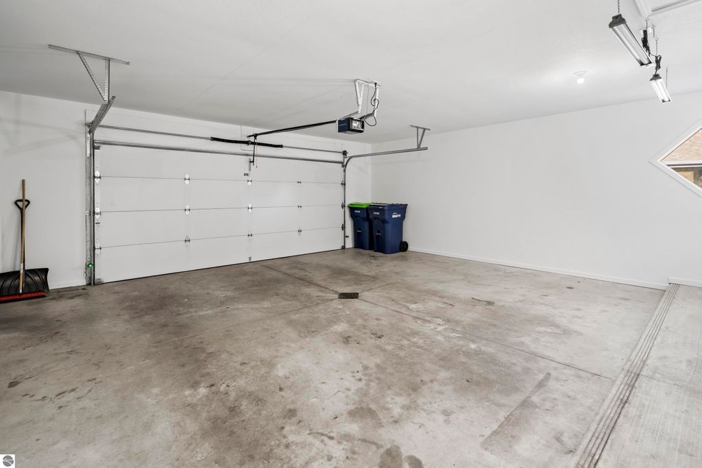 Spacious, clean 2-car garage with garage door, concrete floor, and storage tools, part of the 2-bedroom condo listing at 3756 Country Club Drive, Traverse City, MI.