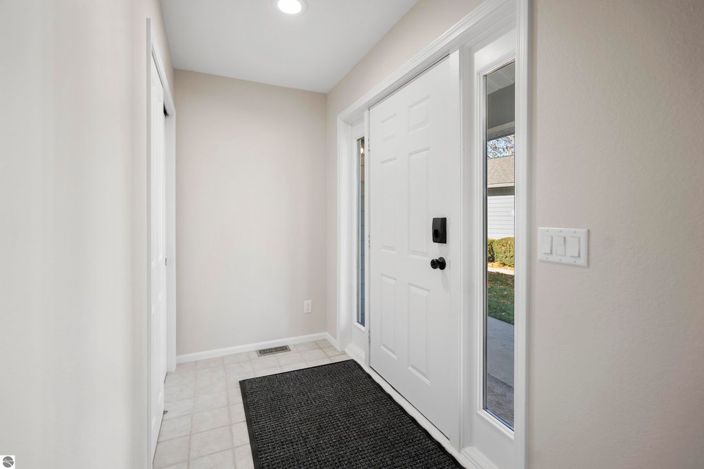 Entryway of a modern 2-bedroom condo at 3756 Country Club Drive, featuring a white front door with sidelights, beige walls, and tile flooring, showcasing a welcoming and bright atmosphere.