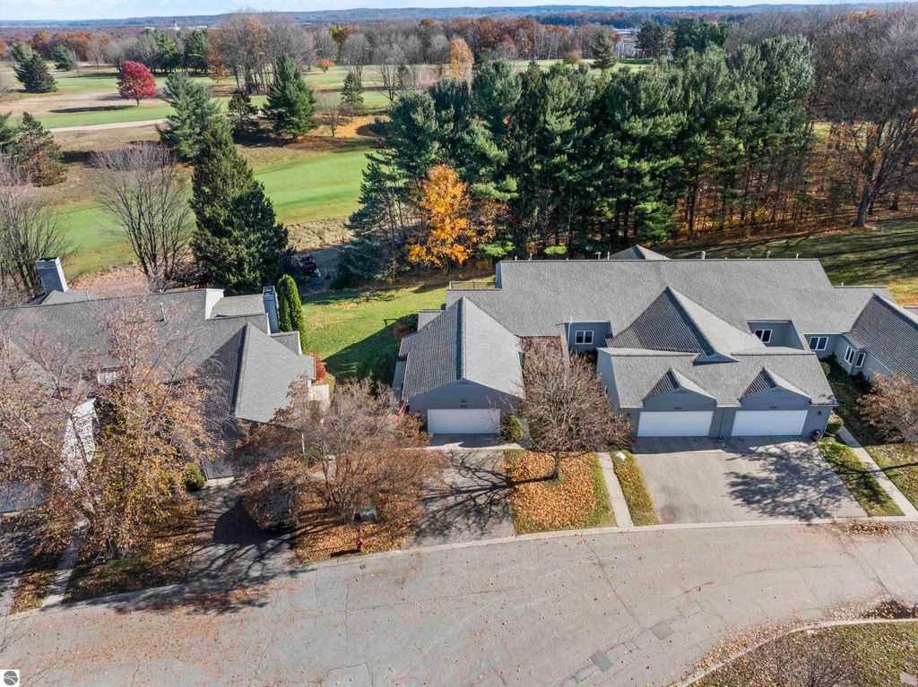 Aerial view of a condo community in Traverse City, Michigan, featuring well-maintained homes, mature trees, and a golf course in the background, showcasing the peaceful setting of 3756 Country Club Drive.