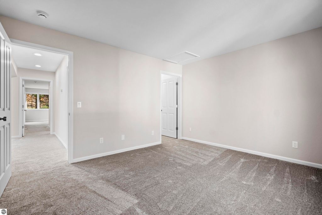 Light-filled interior of a 2-bedroom condo in Traverse City, featuring freshly painted walls, plush carpeting, and doorways leading to adjacent rooms, highlighting spacious living areas and natural light.