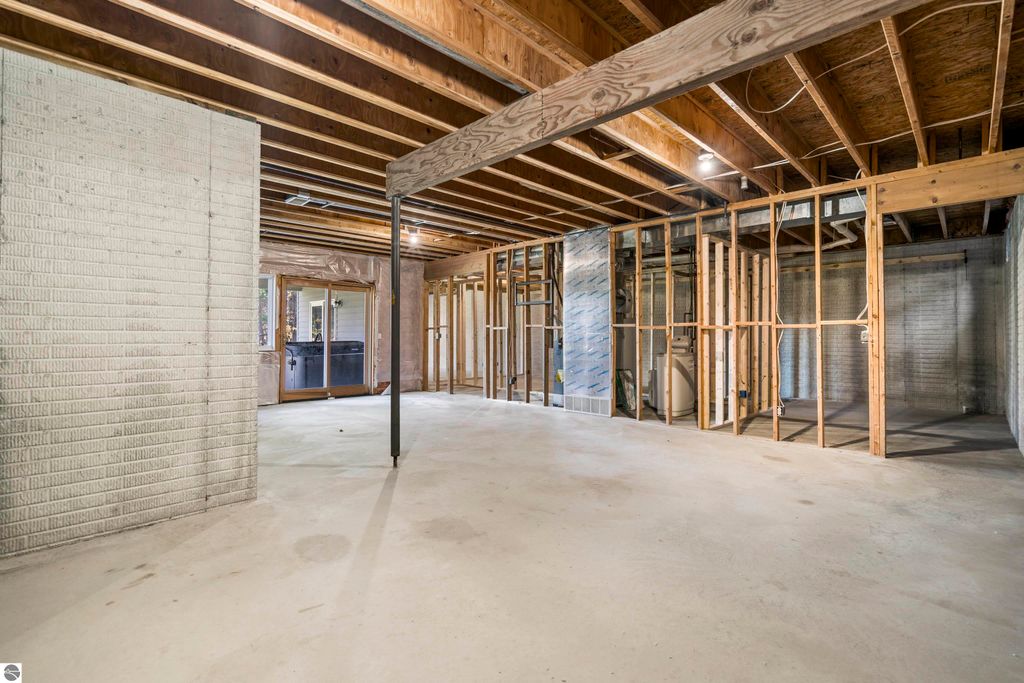 Unfinished lower level of a condo at 3756 Country Club Drive, featuring exposed framing, concrete flooring, and a large window overlooking the outdoor area, ideal for customization and additional living space.