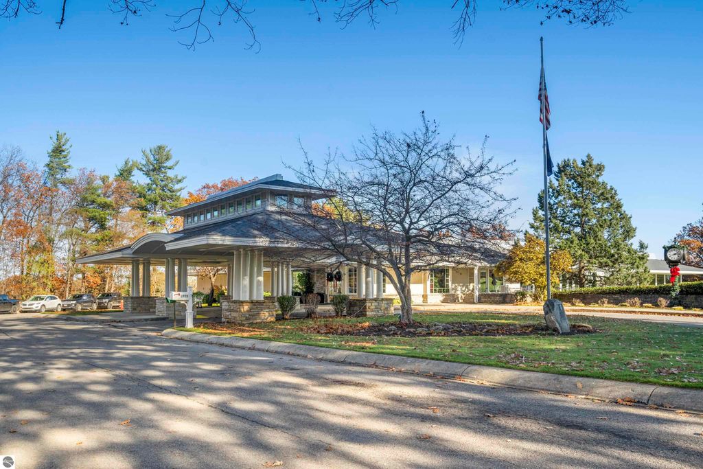Exterior view of the Country Club Woods community entrance in Traverse City, featuring a modern architectural design, landscaped surroundings, and flagpole, highlighting the tranquil setting near the condo listing at 3756 Country Club Drive #9.