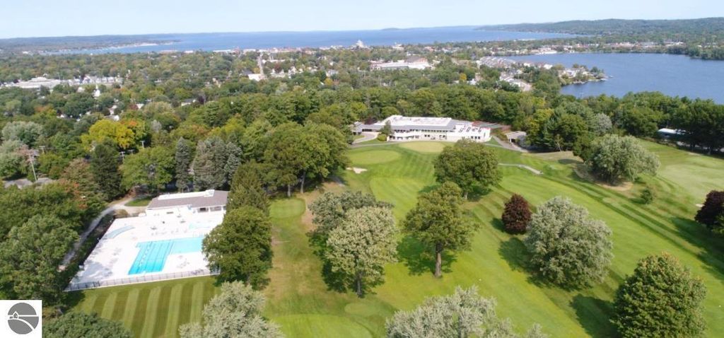 Aerial view of the Country Club Woods community in Traverse City, showcasing a golf course, swimming pool, and lush greenery, emphasizing the tranquil setting near 3756 Country Club Drive #9 condo listing.