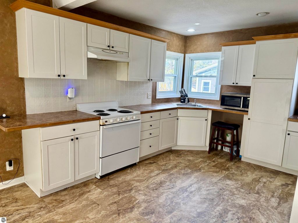 Spacious kitchen with white cabinetry, modern appliances, and dining area, showcasing the interior of the property at 711 Francisco Avenue, Alma, MI.
