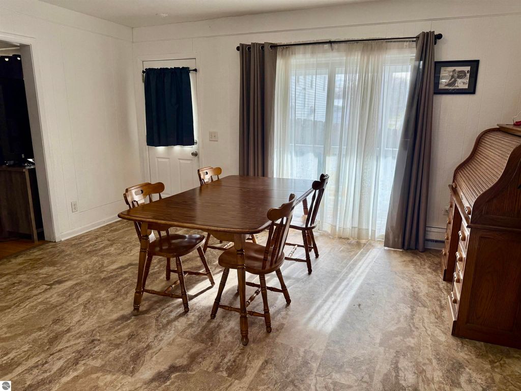 Dining area with a wooden table and chairs, featuring natural light from sliding glass doors, in a home located at 711 Francisco Avenue, Alma, MI.