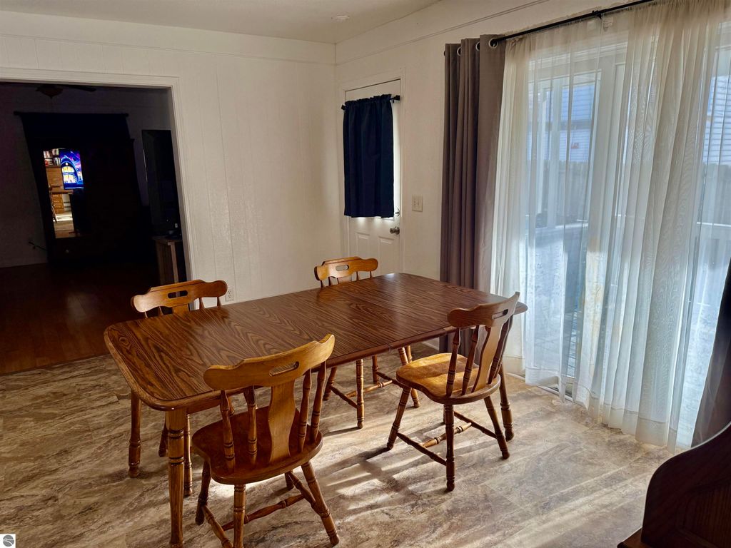Spacious dining area with wooden table and chairs, natural light from large windows, showcasing the interior of the property at 711 Francisco Avenue, Alma, MI.