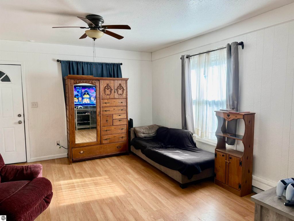 Living room interior of 711 Francisco Avenue, featuring a wooden wardrobe with mirror, a dark sofa, a red armchair, and natural light from windows, emphasizing spaciousness and comfort for potential buyers.