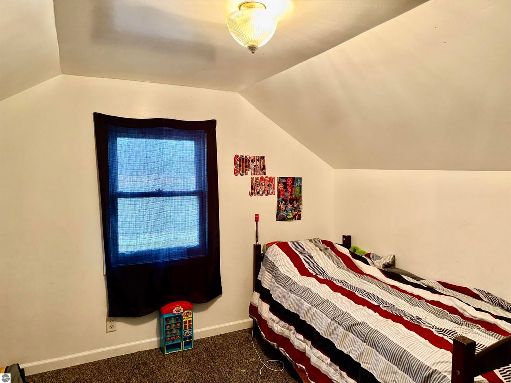 Bedroom featuring a twin bed with striped bedding, a window with blue curtains, and a wall decorated with children's posters and the name "Sophia Jessica," ideal for a cozy living space in a rental property.