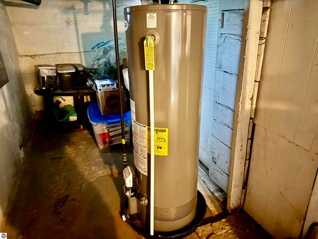 Water heater in basement of investment property at 711 Francisco Avenue, Alma, MI, with storage items nearby.