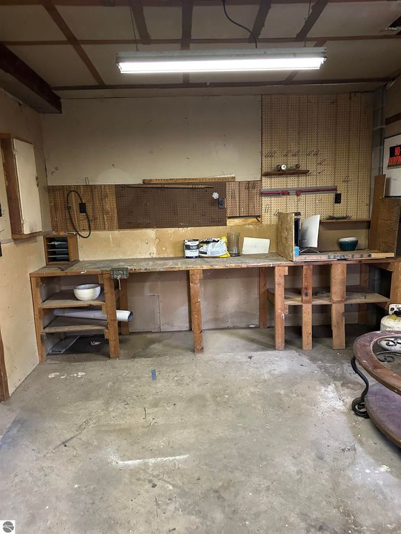 Workshop space with wooden workbench, pegboard wall, and tools, suitable for storage or gardening projects in a home on 14.5 acres in Evart, MI.