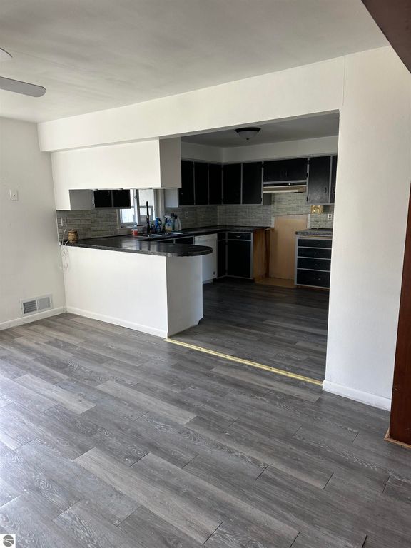 Interior view of a home at 4419 10 Mile Road, featuring a modern kitchen with black cabinetry, an open layout, and new flooring, suitable for family living or as a getaway property.
